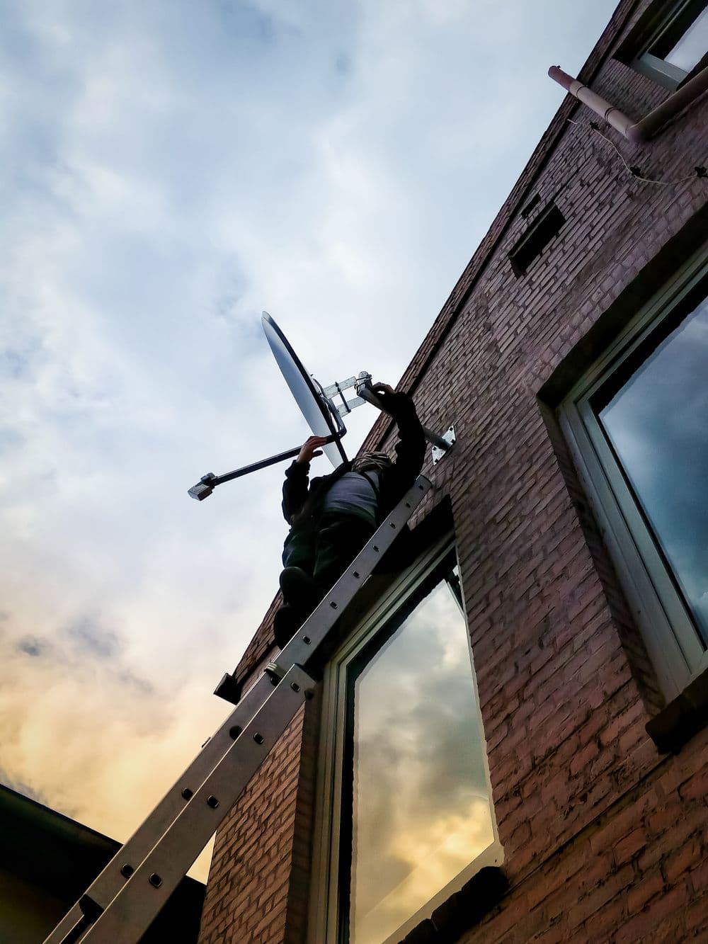 A technician installing a satellite dish on a building